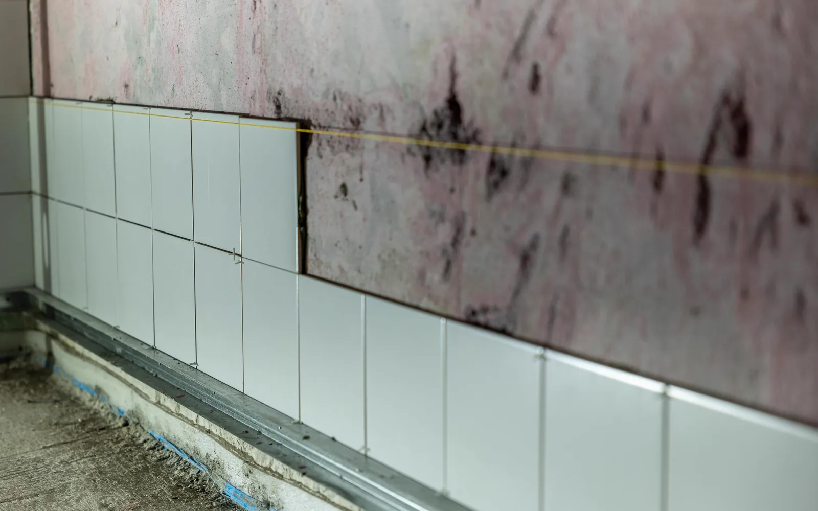 Carreleur posant du carrelage grand format dans une salle de bains moderne