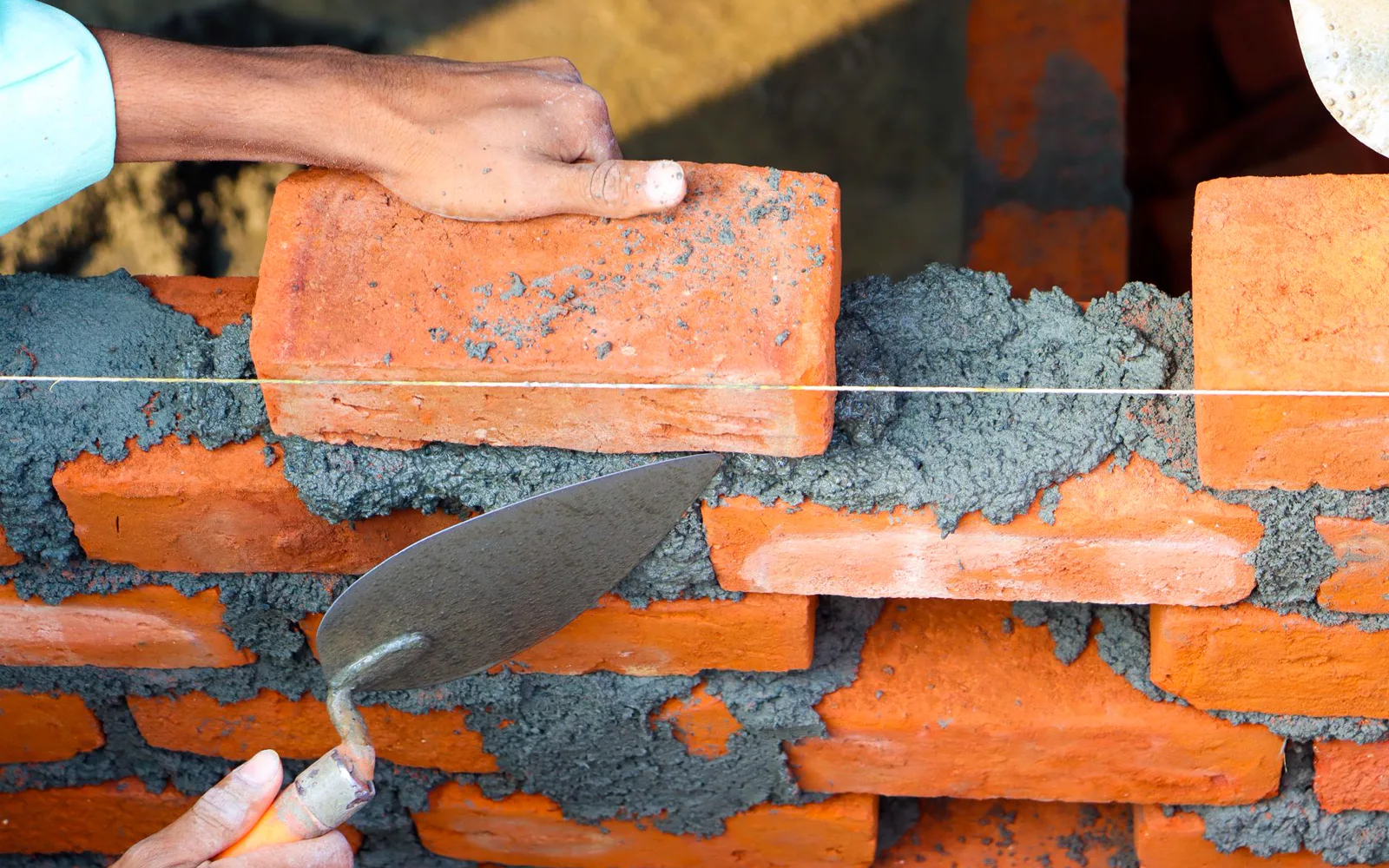 Maçon montant un mur en parpaings sur un chantier d'extension de maison