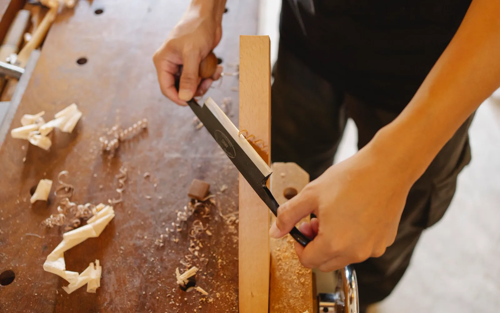 Menuisier en train de travailler une pièce de bois dans son atelier