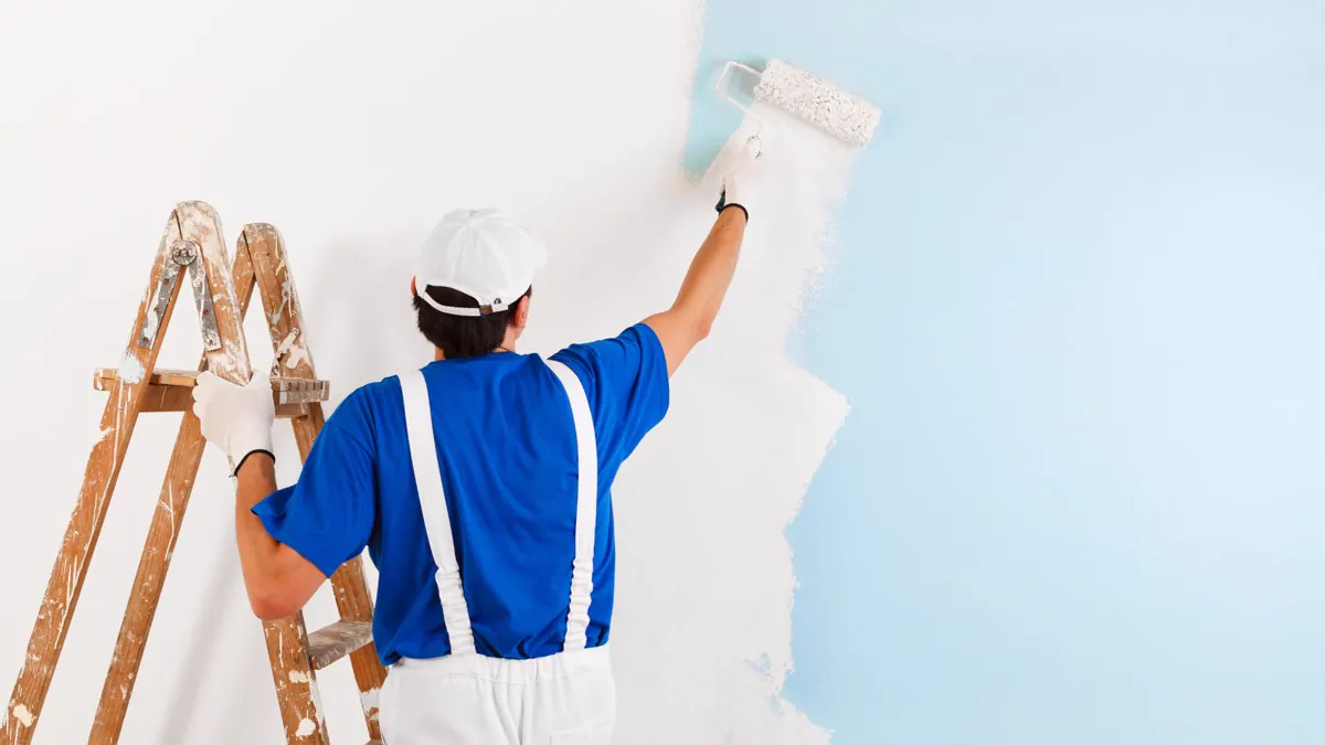 Peintre en bâtiment appliquant la peinture au rouleau sur un mur