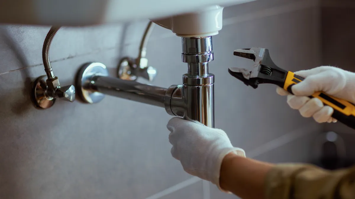 Plombier resserrant le siphon d’un lavabo à la clé