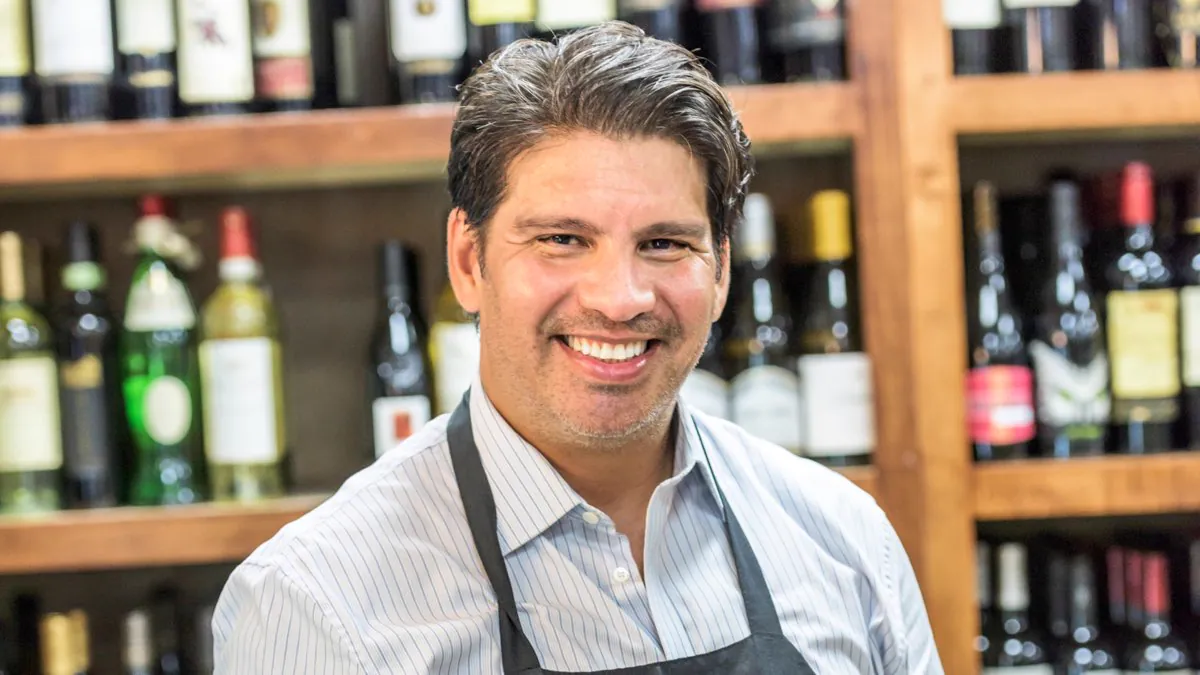 Caviste souriant devant ses rayons de vins