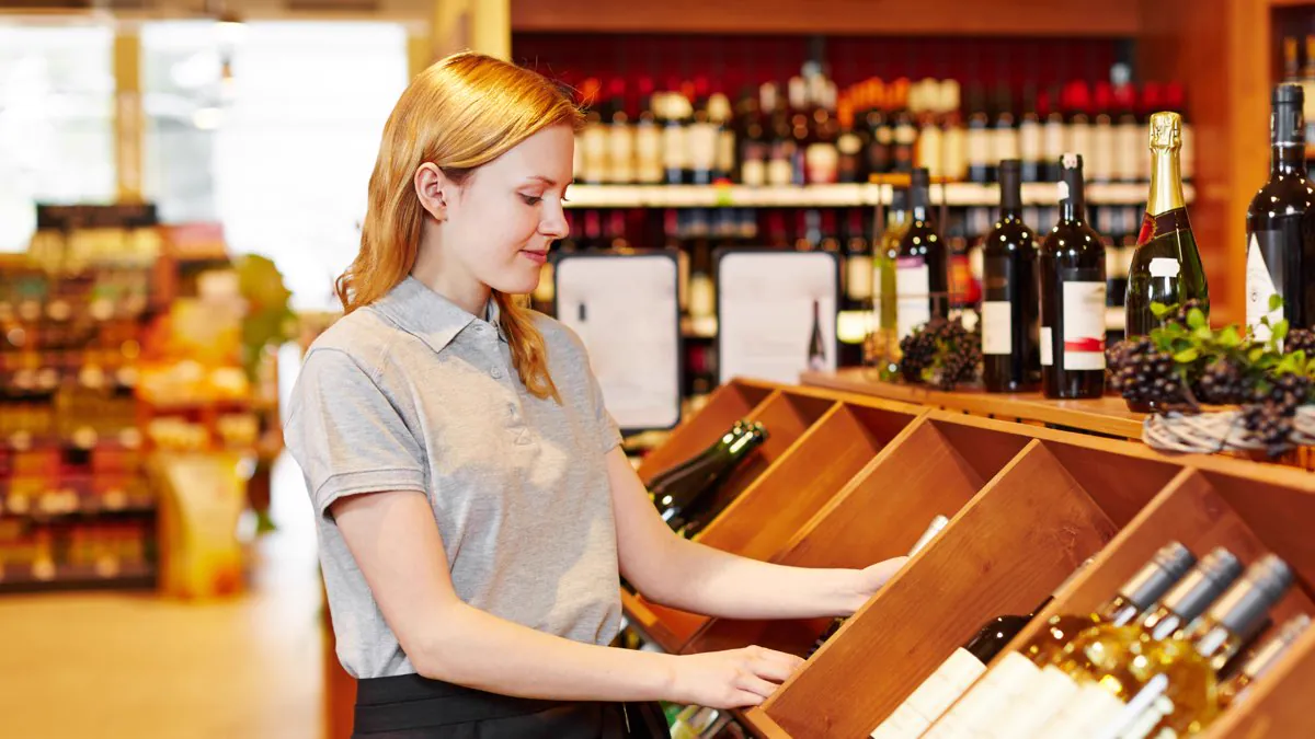 Vendeuse disposant des bouteilles dans une cave à vin