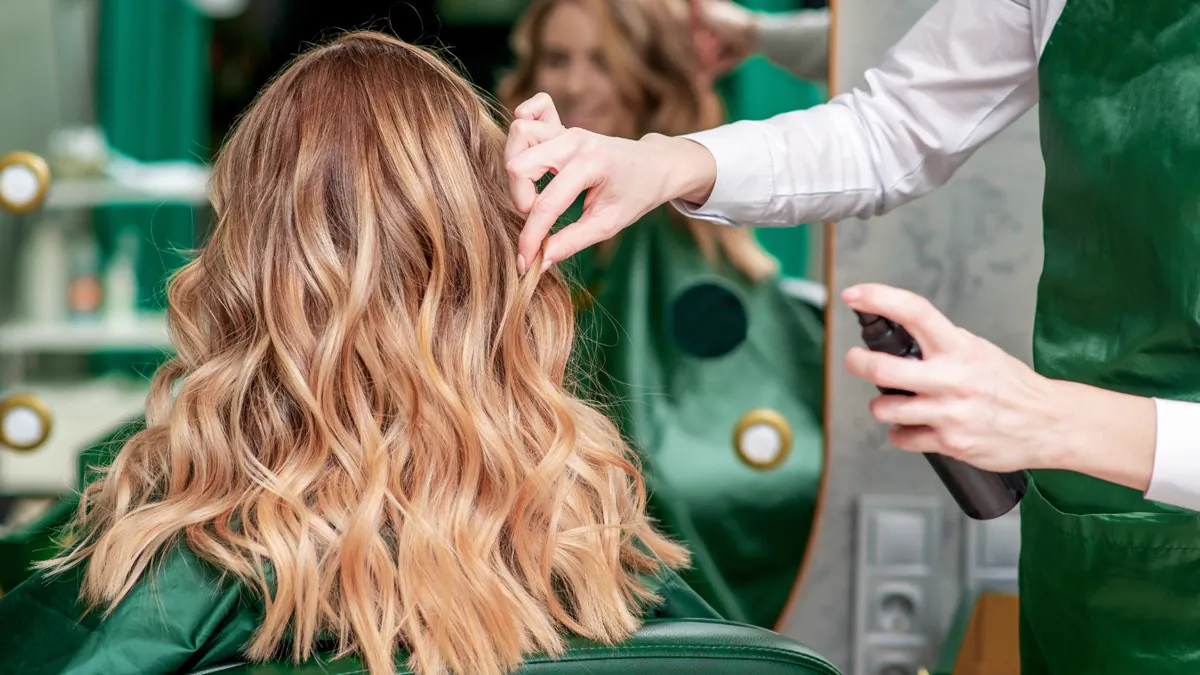 Coiffeuse réalisant un balayage et une mise en forme en salon