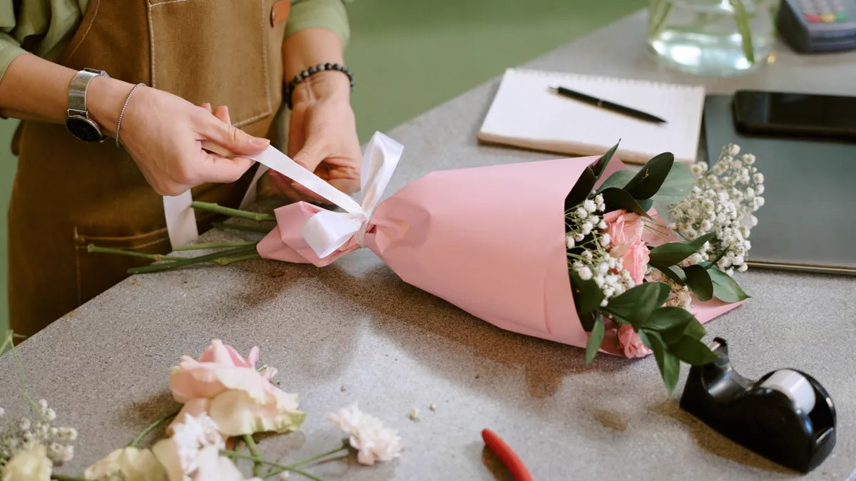 Fleuriste emballant un bouquet de roses au comptoir