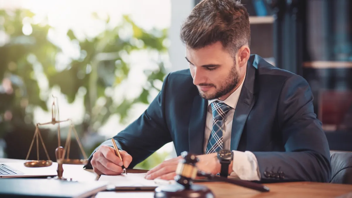 Avocat en costume signant un document, balance de la justice