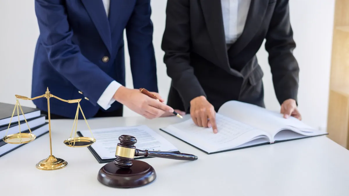 Deux avocats étudiant un dossier, balance et marteau de justice