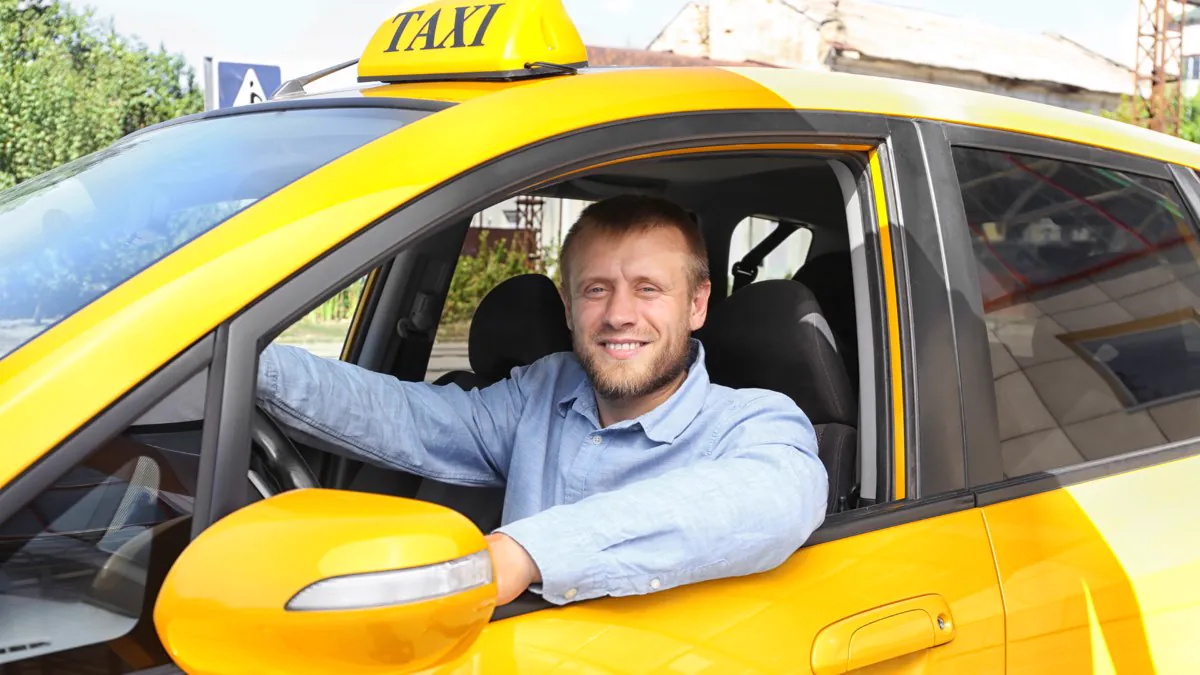 Chauffeur de taxi souriant au volant de son véhicule