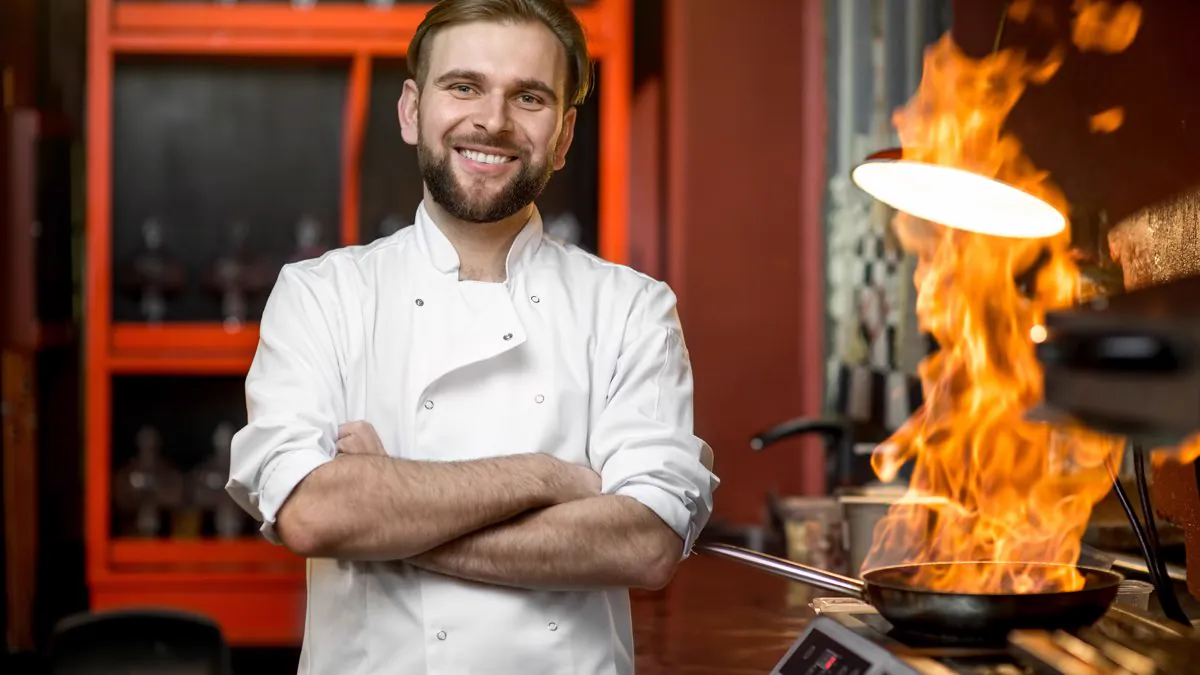Cuisinier souriant préparant un plat flambé