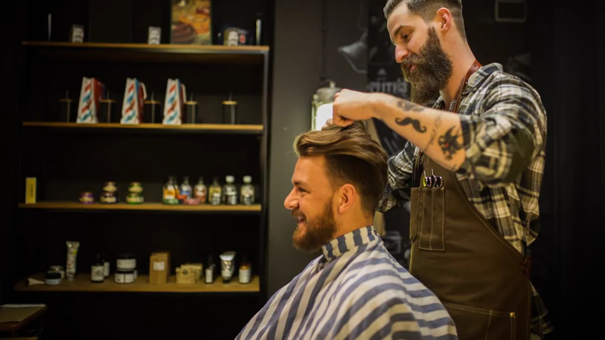 Barbier coiffant un client barbu dans son salon