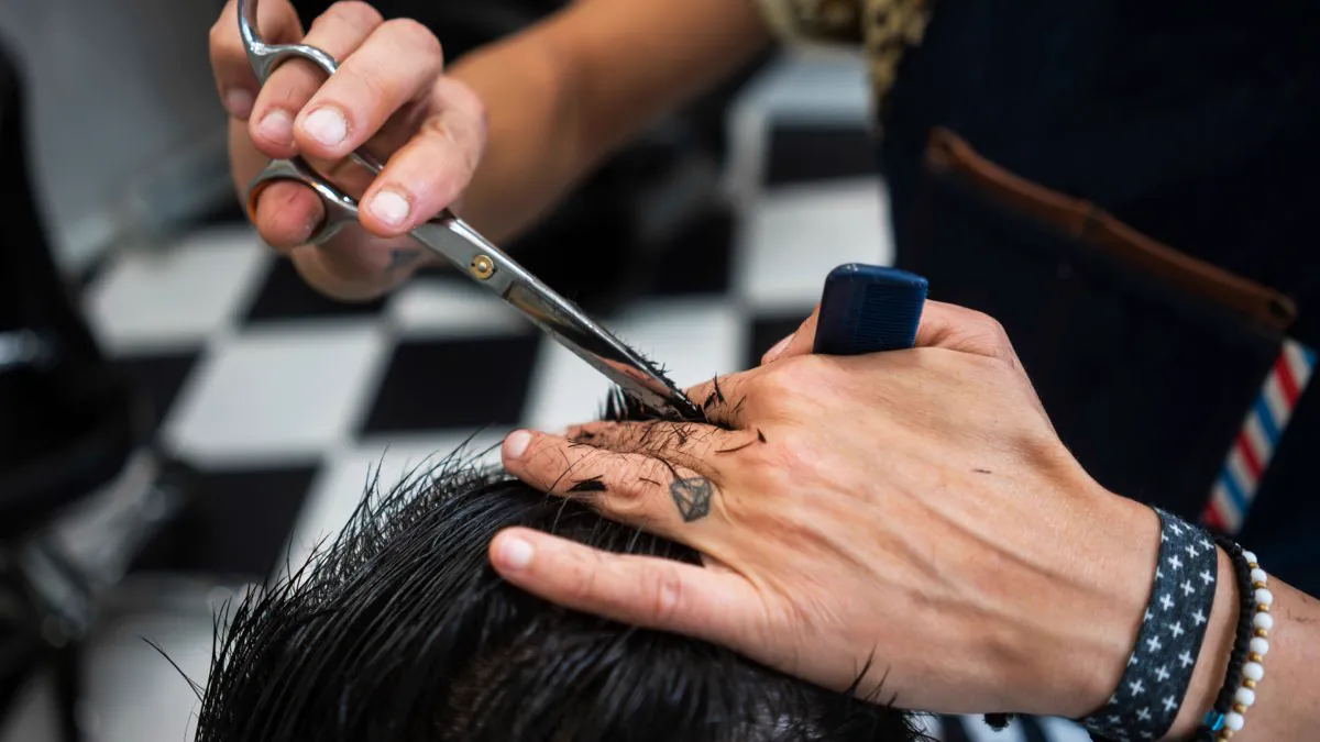 Coupe de cheveux aux ciseaux et peigne chez le barbier