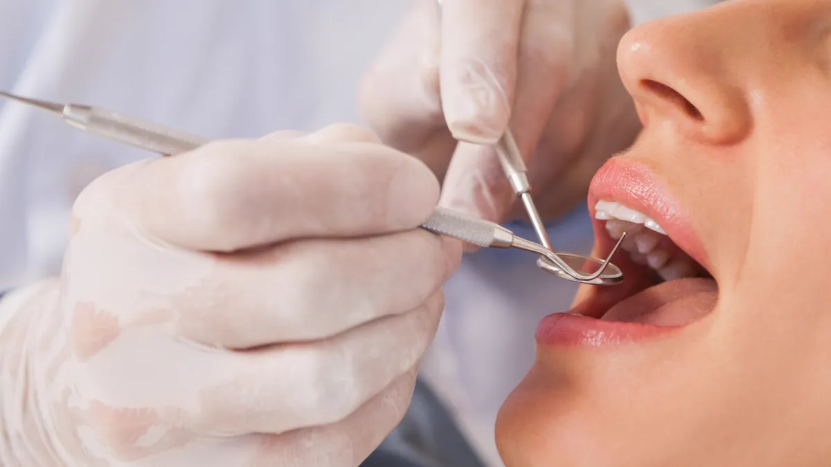 Dentiste examinant les dents d’une patiente au miroir buccal