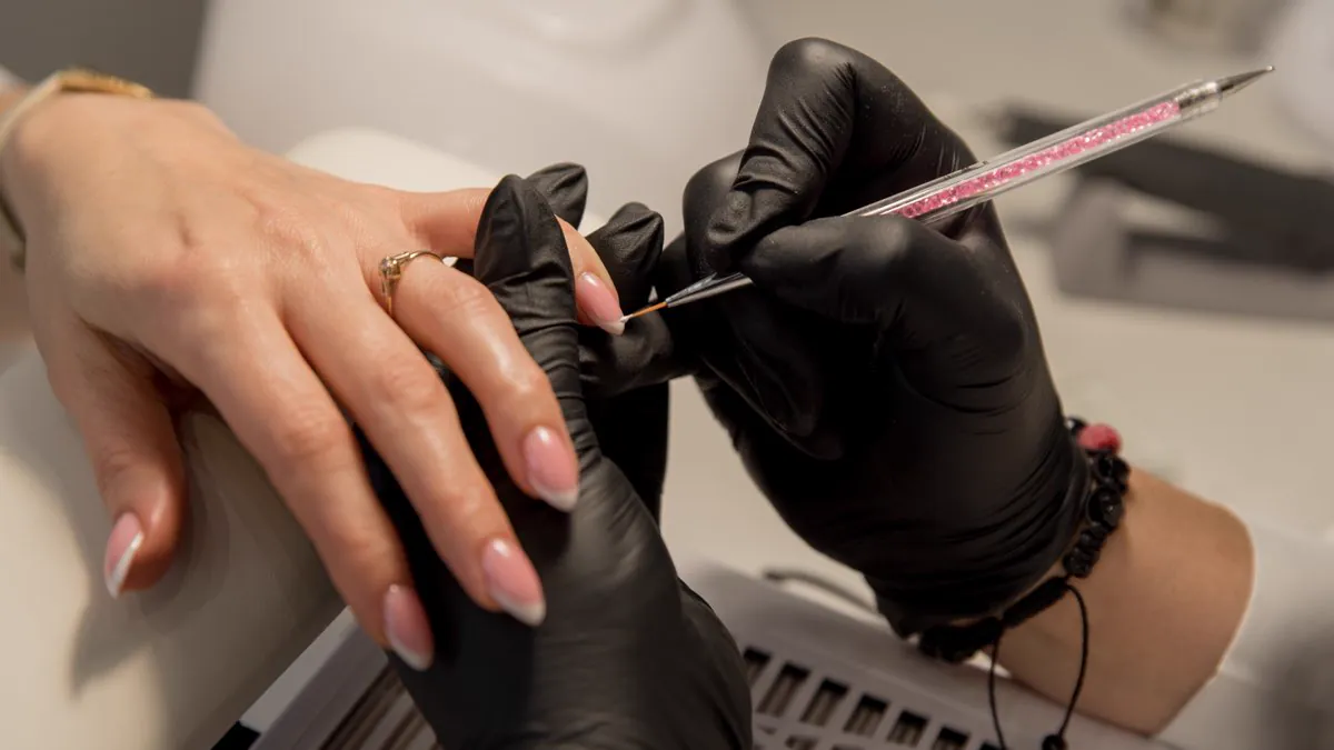 Prothésiste ongulaire posant une décoration sur les ongles
