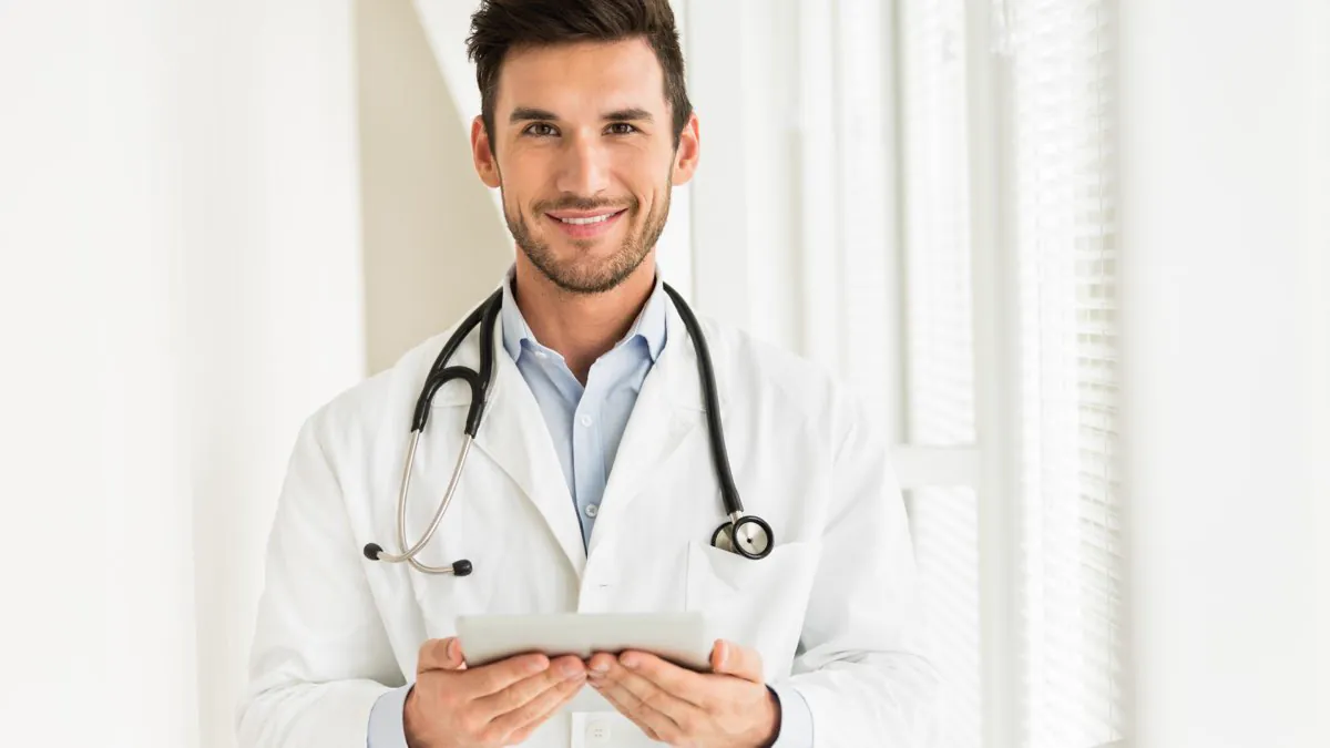Médecin au stéthoscope consultant un dossier sur tablette