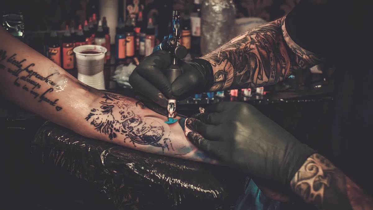 Tatoueur réalisant un tatouage sur l’avant-bras d’un client